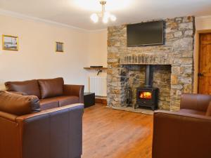 a living room with couches and a stone fireplace at Ysgubor Wen in Burry Port