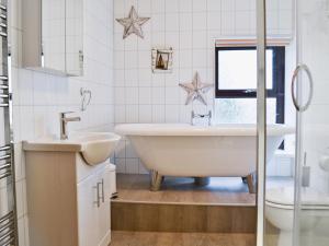 a white bathroom with a tub and a sink at Ysgubor Wen in Burry Port +12 photos