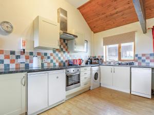 a kitchen with white cabinets and a wooden floor at The Cartlinhay - Uk35756 in Bideford