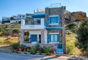 a house with blue shutters on a hill at Seafront Villa Moments, by Estia in Mochlos