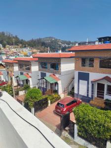 a red car parked in a parking lot in front of houses at Blue Pearl Cottage in Ooty