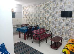a dining room with chairs and a table and a tv at Blue Pearl Cottage in Ooty