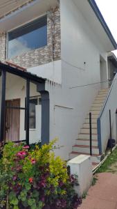 a white house with stairs and flowers in front of it at Blue Pearl Cottage in Ooty +10 photos