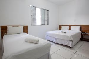 a bedroom with two beds with white sheets and a window at Rede Andrade Royal in Itabuna
