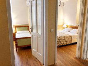 a bedroom with two beds and a door leading into a room at Batthyány Kastélyszálló in Zalacsány
