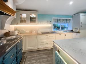 a kitchen with white cabinets and blue walls at Failte in Colintraive