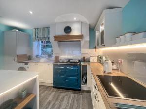a kitchen with white cabinets and a blue stove at Failte in Colintraive