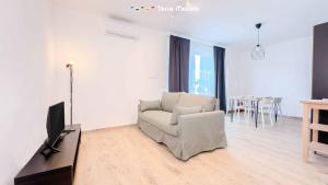 a white living room with a chair and a television at Il Posto Perfetto, Terre Marine in Corvara