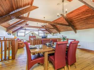 a dining room with a wooden table and red chairs at The Threshing Barn - Uk35754 in Bideford