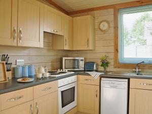 a kitchen with wooden cabinets and a stove and microwave at Hawthorne in Woolfardisworthy