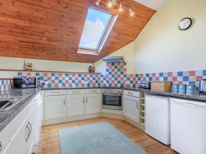 a large kitchen with white cabinets and a window at The Granary - Uk35755 in Bideford