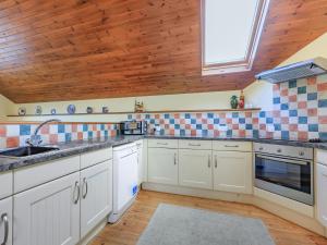 a kitchen with white cabinets and a wooden ceiling at The Granary - Uk35755 in Bideford +9 photos