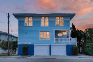 a blue house with a clock in the window at SEA2SKY Ocean front private pool and spa in Kure Beach