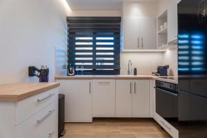 a kitchen with white cabinets and black appliances at SithoniaRS Boho Edition Luxury Roofgarden II in Neos Marmaras
