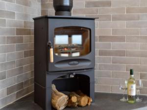 a wood stove with a tv and a bottle of wine at Sweet Meadow Lodge in Llandrindod Wells