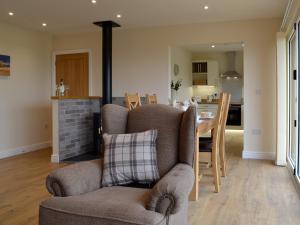 a living room with a chair and a table and a kitchen at Sweet Meadow Lodge in Llandrindod Wells