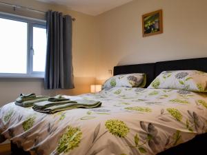 a bed with a blanket and pillows on it at Sweet Meadow Lodge in Llandrindod Wells +16 photos