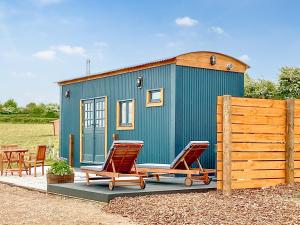 a blue tiny house with two chairs and a table at Walkeridge Farm in Reading