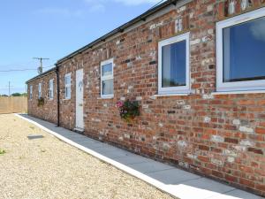 a brick building with white windows and a sidewalk at Dotterel Cottage - Uk39264 in Reighton