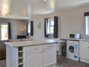 a kitchen with white cabinets and a washer and dryer at Dotterel Cottage - Uk39264 in Reighton