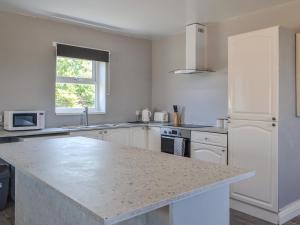 a kitchen with white cabinets and a counter top at Dotterel Cottage - Uk39264 in Reighton +8 photos
