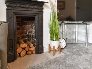 a fireplace with a plant and a clock and logs at Mills Croft in Hognaston