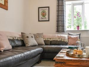 a living room with a leather couch and a table at Mills Croft in Hognaston +22 photos