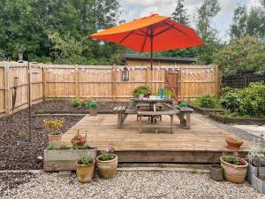 a wooden deck with a table and an umbrella at Mills Croft in Hognaston