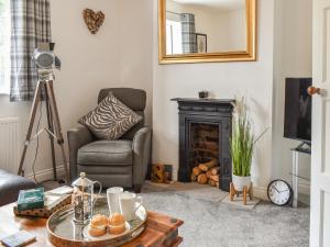 a living room with a chair a table and a fireplace at Mills Croft in Hognaston