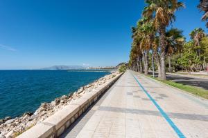 a sidewalk next to the water with palm trees at La casa del Pan in Málaga