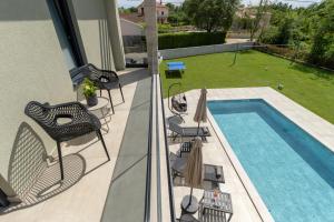 a balcony with a swimming pool and chairs next to a house at Casa Presika- Wellness, Fiber Net & Peace in Labin