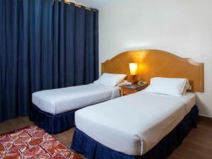 2 camas en una habitación de hotel con cortinas negras en Safeer Hotel Suites, en Mascate