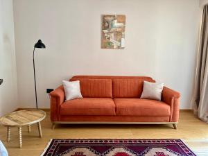 an orange couch in a living room with a rug at Hotel Carmen in Eforie Nord +49 photos