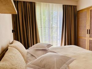 a bedroom with a bed with pillows and a window at Hotel Carmen in Eforie Nord
