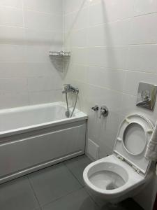 a white bathroom with a toilet and a bath tub at Orbi Residence in Itʼkhvisi