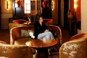 a woman sitting in a chair holding a camera at Hôtel La Bourdonnais by Inwood Hotels in Paris
