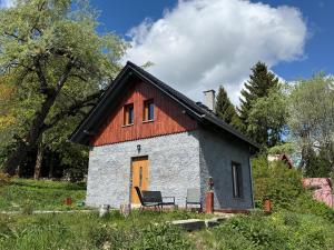 a small house with a orange door and a chair at Agroturystyka Monte Luna - domki in Czarnów
