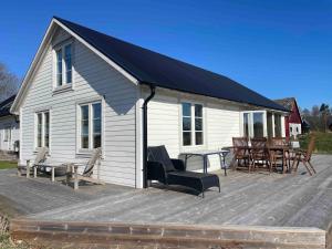 a white house with a deck with a table and chairs at Bergsbo Lodge in Halmstad
