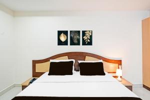 a bedroom with a white bed with a wooden headboard at Hotel O Anantapur in Anantapur