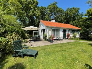 a small house with an umbrella and a lawn at Holiday home Zeeroos in Koudekerke