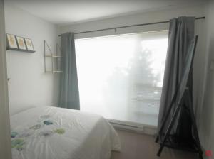 a bedroom with a window with a white bed and a window with a curtain at Elite Townhouse at the Shipyaards in North Vancouver