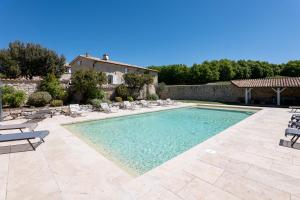 a swimming pool with chairs and a house at Bastide de Marius in Redortiers