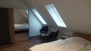 a bedroom with a bed and two chairs and a mirror at Ferienwohnung an der Holtemme in Derenburg
