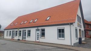 a white building with an orange roof on a street at Ferienwohnung an der Holtemme in Derenburg