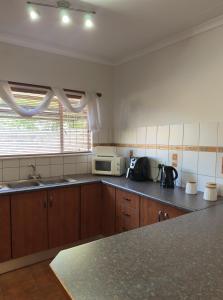 a kitchen with a sink and a microwave at Anja Guesthouse in Modimolle
