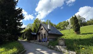a small house with two blue chairs next to a road at Agroturystyka Monte Luna domki in Czarnów