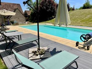 a swimming pool with a umbrella and chairs and a table and chairsktop at Moulin de Bas Couleur in Villedômer