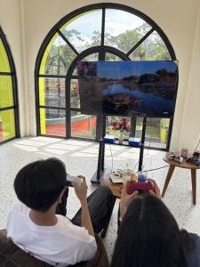 a group of people sitting in a room playing a video game at Onsen Resort Kaliurang in Mantaak