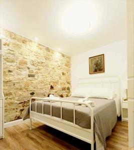 a bedroom with a white bed and a stone wall at Fiore Kampielo Apartment in Corfu