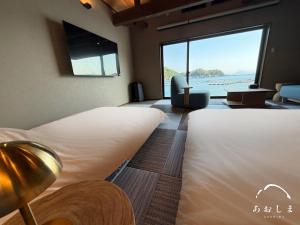 a bedroom with two beds and a view of the ocean at Aoshima あおしま in Kameshima